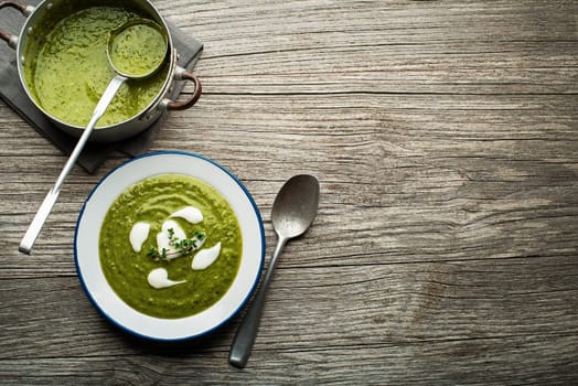 Fresh healthy green soup on wooden background overhead shoot.