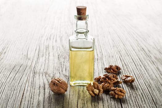Walnut oil in a glass bottle on a wooden background