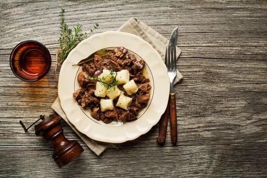 Fresh fried chicken liver with onion and gnocchi on wooden table