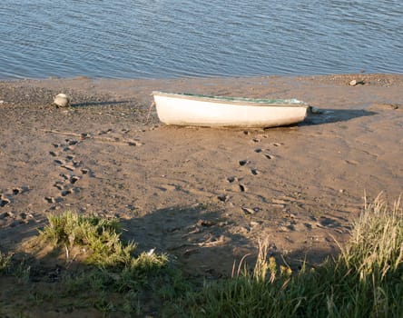 a parked row boat vessel on the beach with footprints too and from it Essex  England  UK