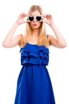 Beautiful woman in blue dress using sunglasses with a hearth shape, isolated over white background
