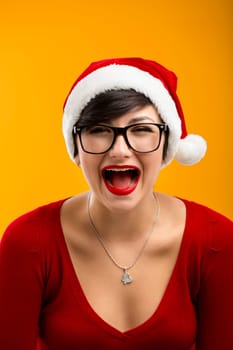 Beautiful nerd girl wearing a santa hat and holding a gift, against yellow background