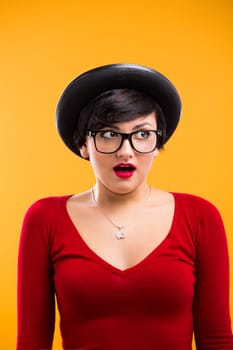 Beautiful nerd girl wearing a santa hat and holding a gift, against yellow background