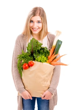 Beautiful blonde woman carrying a bag full of vegetables with thumbs up, isolated over white background