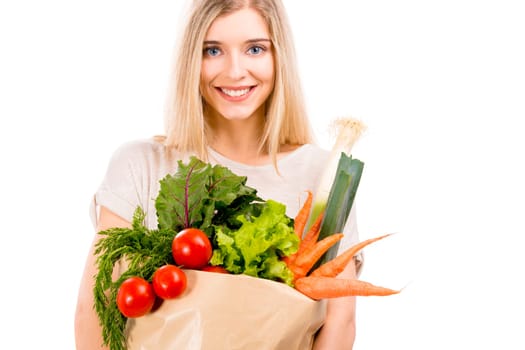 Beautiful blonde woman carrying a bag full of vegetables with thumbs up, isolated over white background