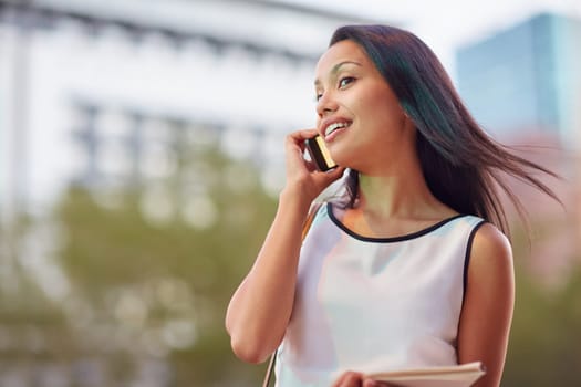 A young businesswoman talking on her phone while standing in front of an office block