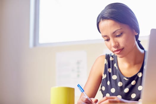 A young woman writing while sitting in her office