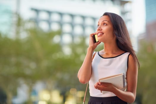 A young businesswoman talking on her phone while standing in front of an office block