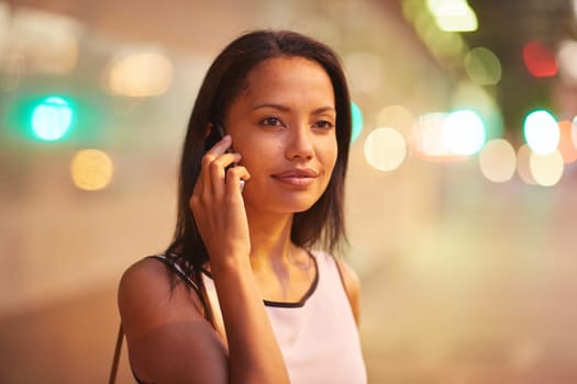 A young businesswoman talking on her phone while standing in front of an office block