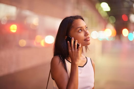 A young businesswoman talking on her phone while standing in front of an office block