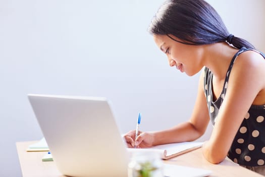A young woman writing while sitting in her office