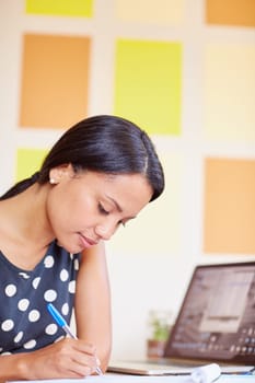 A young woman writing while sitting in her office