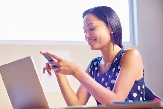 A young woman texting while sitting in her office