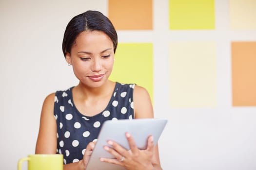 A young woman working on her digital tablet in her office