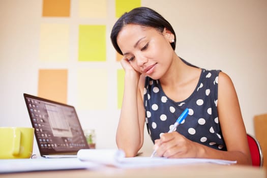 A young woman writing while sitting in her office