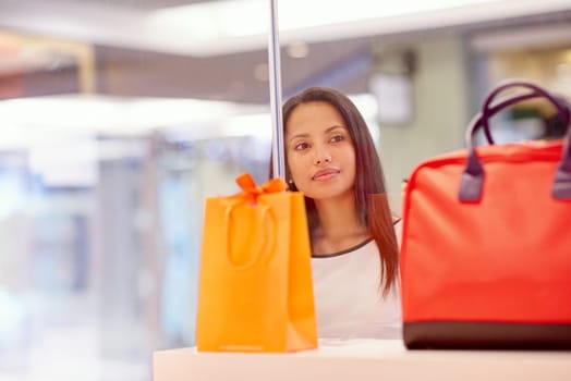 A young woman looking at a handbag through a shop window