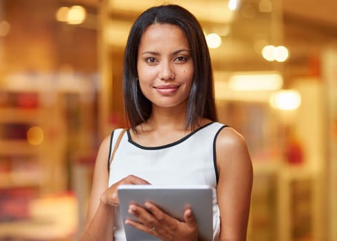 A beautiful young woman holding a tablet while standing outdoors in the city at night