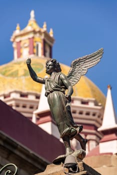Small angel statue with the dome of the cathedral of Puebla, Mexico in the background