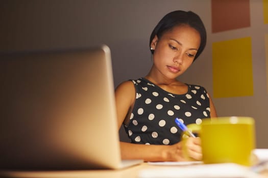 A young woman writing while sitting in her office at night