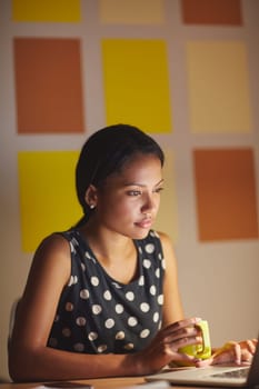 A young woman working on her laptop in her office at night