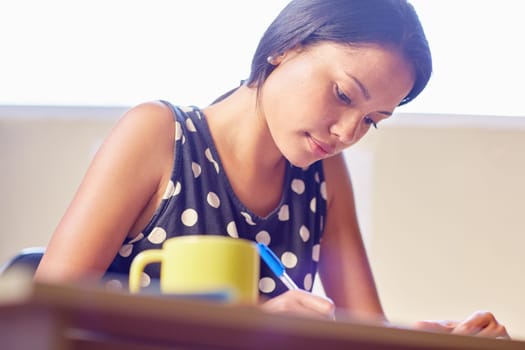 A young woman writing while sitting in her office