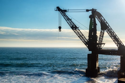 Silhouette of an old abandoned crane in the Pacific Ocean in Vina del Mar, Chile