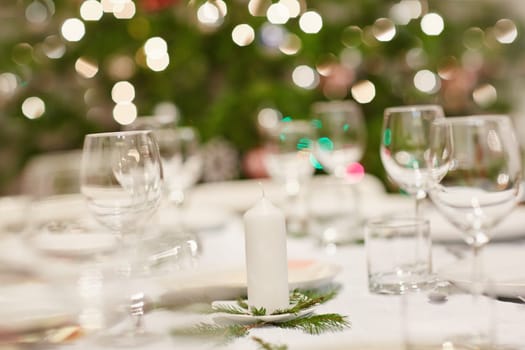 Closeup shot of a table set with glassware, plates and cutlery for a Christmas dinner
