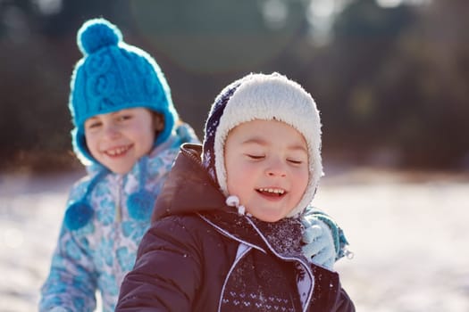 Candid shot of little boy and girl siblings outdoors on a sunny winter's day