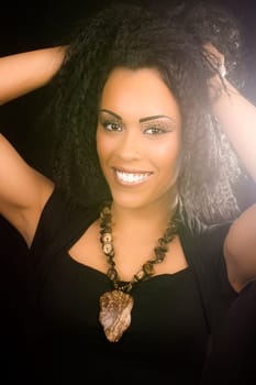Beautiful smiling black woman with curly hair on black background.