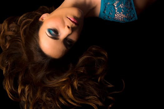 The woman with beautiful long hair is lying down on black background.