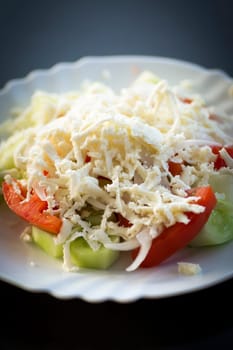 Traditional serbian salad on white plate on dark background.