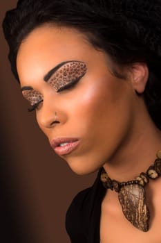 Beautiful young black woman with animal print eye shadow on closed eyes.