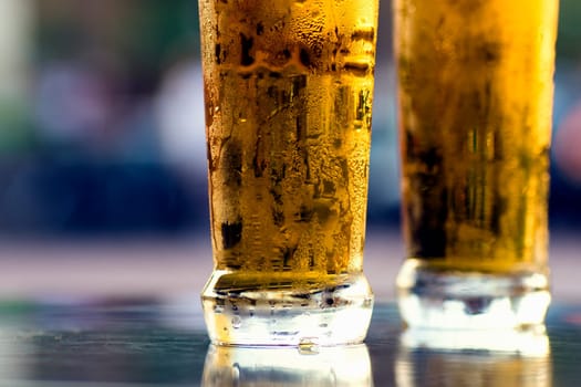 Two cold lager light beers on table on blue background.