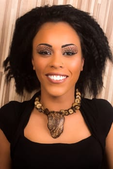 Beautiful smiling black woman is lying down on the laminated floor.