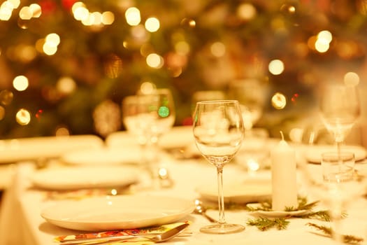 Closeup shot of a table set with glassware, plates and cutlery for a Christmas dinner