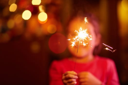 A happy little girl playing with a sparkler