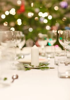 Closeup shot of a table set with glassware, plates and cutlery for a Christmas dinner
