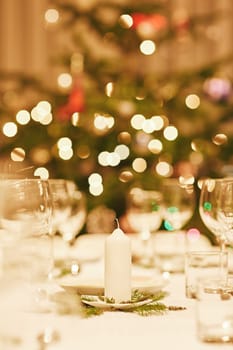 Closeup of a christmas candle on a festive table with bokeh in the background