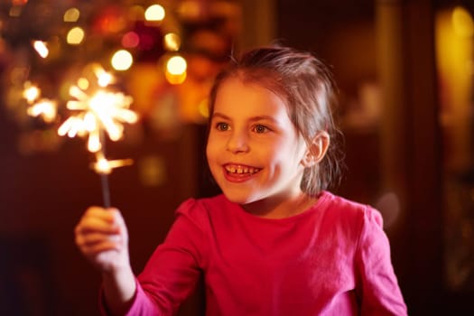 A happy little girl playing with a sparkler