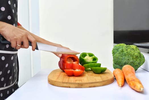 Woman slicing peppers and cooking in the kitchen
