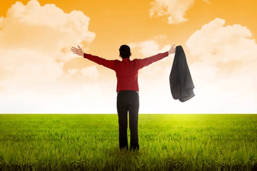 Man open his suit, raise arms on the meadow. Business freedom conceptual