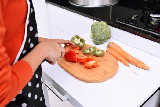Woman slicing peppers and cooking in the kitchen