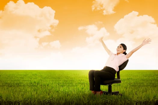 Business woman sitting on chair on the meadow. Business freedom concept