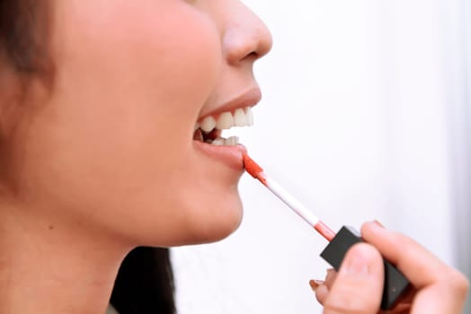 Close-up beautiful woman applying red lipstick on her lips when makeup