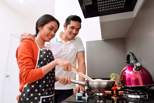 Portrait of asian couple smiling and cooking together in the kitchen