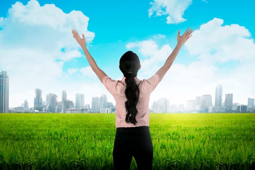 Backview of asian business woman looking the city while raise her hand up
