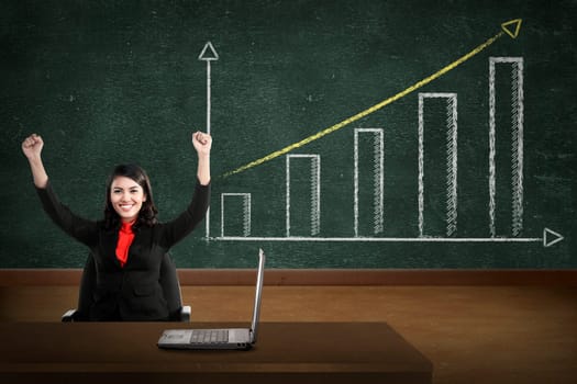 Business person smile over increasing graph drawing on chalk board
