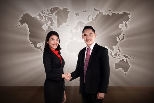 Man and woman shaking hand with world map as background