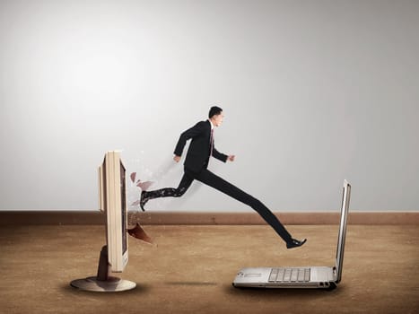 Business man with long leg out from computer desktop to laptop. Gadget switch concept