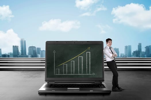 Asian business man leaning on big laptop, show report